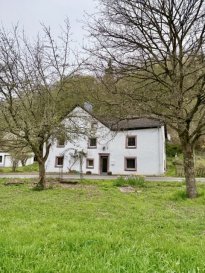 Schmuckstück im Naturparadies ? Wohnen an der Our im Naturpark Südeifel

Stellen Sie sich vor, Sie öffnen morgens die Fenster und hören nichts als das sanfte Rauschen der Our und das Zwitschern der Vögel. Eingebettet in die unberührte Natur des Naturpark Südeifel erwartet Sie ein ganz besonderes Zuhause ? ein Rückzugsort für Naturliebhaber, Ruhesuchende und Individualisten.

Dieses charmante Einfamilienhaus vereint Ursprünglichkeit mit Komfort und bietet Ihnen vielfältige Nutzungsmöglichkeiten ? ob als großzügiges Familienrefugium, Mehrgenerationenhaus oder als zwei separate Wohneinheiten.

Das Wichtigste auf einen Blick
Wohnfläche: ca. 144 m² auf zwei Etagen
Grundstück: großzügig, direkt an der Our gelegen
Bauweise: massive Bruchsteinbauweise
Aufteilung:
Obergeschoss: ca. 77 m²
Erdgeschoss: ca. 65 m²
ideal zur Nutzung als zwei Wohneinheiten
Zimmer: 4 Schlafzimmer
Bäder: 2 Badezimmer
Fenster: doppelt verglast (1998)
Heizung: Ölheizung (2009) mit ca. 3.000 Liter Tank
Außenbereich: 4 Terrassen mit traumhaften Ausblicken
Parkmöglichkeiten: 2 Garagen + 2 Stellplätze
Dach: Speicher mit nicht ausgebautem Spitzboden
Technik: SAT-TV & WLAN vorhanden
Zustand: gepflegt ? sofort bezugsfertig
Ein Zuhause mit Perspektive

Die durchdachte Aufteilung eröffnet Ihnen maximale Flexibilität: Nutzen Sie das Haus als großzügiges Einfamilienhaus oder teilen Sie es in zwei eigenständige Wohneinheiten ? perfekt für Mehrgenerationenwohnen oder zur teilweisen Vermietung.

Die zwei Terrassen bieten zu jeder Tageszeit den passenden Platz, ob Frühstück in der Morgensonne oder ein Glas Wein mit Blick in die Natur am Abend. Zusatzfläche mit außergewöhnlichem Potenzial: Ein echtes Highlight dieser Immobilie ist die Möglichkeit, zusätzlich ca. 5.093m² Grundstück direkt an der Our zu erwerben.

Diese Fläche eröffnet Ihnen vielfältige Perspektiven:
Pferdehaltung oder Tierhaltung
Freizeit- und Erholungsfläche
Naturverbundenes Wohnen, z. B. mit einem Tiny House (nach individueller Genehmigung)
Selbstversorgung oder kleine Viehzucht

Ein Paradies für Tierliebhaber, Selbstversorger oder Investoren mit Vision, direkt am Wasser gelegen und eingebettet in eine einzigartige Naturlandschaft. 
Lage, Natur pur & absolute Ruhe

Die Immobilie liegt in einmaliger Naturlage direkt an der Our, umgeben von Wäldern, Wiesen und sanften Hügeln. Der Naturpark Südeifel steht für eine der ursprünglichsten Landschaften Deutschlands ? ideal für Wanderer, Radfahrer und alle, die dem Alltag entfliehen möchten.

Hier genießen Sie absolute Ruhe und Privatsphäre ? und sind dennoch gut angebunden.

Fazit

Ein seltenes Angebot für Menschen mit Sinn für Natur, Raum und Lebensqualität. Ob als privates Refugium, Mehrgenerationenlösung oder Kombination aus Wohnen und Vermieten, dieses Haus bietet Ihnen zahlreiche Möglichkeiten.

Jetzt besichtigen & verlieben

Solche Lagen sind rar. Lassen Sie sich dieses besondere Angebot nicht entgehen und vereinbaren Sie noch heute Ihren persönlichen Besichtigungstermin.

Erleben Sie selbst, wie sich Ruhe, Natur und Wohnkomfort perfekt verbinden.