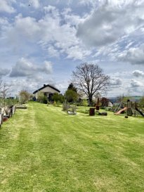 Ein Zuhause mit Raum für Visionen ? Großzügiges Wohnen auf außergewöhnlichem Grundstück

Eingebettet in eine idyllische Naturlandschaft eröffnet sich Ihnen hier eine seltene Gelegenheit: Ein charmantes Wohnhaus mit einem beeindruckenden Grundstück von ca. 3.070 m² ? vollständig als gepflegter Garten angelegt und dennoch durch den Einsatz eines Mähroboters komfortabel zu bewirtschaften. Ein Ort, der Freiheit, Ruhe und Lebensqualität auf einzigartige Weise vereint.

Bereits beim ersten Blick auf das Anwesen wird deutlich: Hier stehen Ihnen alle Möglichkeiten offen. Ob als großzügiges Familienanwesen, Rückzugsort mit viel Privatsphäre oder Kombination aus Wohnen und Arbeiten ? dieses Objekt passt sich Ihren Lebensplänen an.

Das Haus, gewachsen mit der Zeit und modernisiert

Das ursprünglich ca. 1950 erbaute Wohnhaus wurde in den Jahren von 1989 bis 2019 durch einen Anbau sowie umfassende Renovierungen stetig weiterentwickelt. Heute präsentiert sich die Immobilie in einem gutem Zustand mit durchdachter Raumaufteilung und vielseitigen Nutzungsmöglichkeiten.

Auf rund 172 m² Wohnfläche verteilen sich insgesamt fünf Schlafzimmer sowie großzügige Wohnbereiche. Der ausgebaute Speicher bietet zusätzlich Potenzial für zwei weitere Schlafzimmer und wird derzeit als Ankleide genutzt.

Wohnen mit Atmosphäre und Ausblick

Das Herzstück des Hauses bildet der offen gestaltete Wohn- und Essbereich mit direktem Zugang zur Terrasse. Von hier genießen Sie einen wunderschönen Blick ins Ourtal ein Ort, der zu jeder Tageszeit zum Verweilen einlädt.

Die moderne, großzügige Einbauküche wurde 2019 neu installiert und überzeugt durch Funktionalität und Raumangebot. Ebenfalls im Jahr 2019 wurde ein neuer Herd integriert.

Ein Pelletofen im Wohnbereich sorgt nicht nur für behagliche Wärme, sondern unterstützt effizient die bestehende Heizungsanlage.

Das Haus bietet Ihnen:
fünf Schlafzimmer mit Erweiterungsmöglichkeit im Dachgeschoss
zwei Badezimmer (Dusche im Erdgeschoss, Badewanne im Untergeschoss)
ausgebauter Keller ? ideal auch als Einliegerwohnung nutzbar
Bodenbeläge aus Fliesen und Laminat, Echtholz Parkett
neue Haustür
SAT-TV-Anschluss

Die Ölzentralheizung wird durch drei Tanks mit jeweils 2.000 Litern versorgt. Ergänzt wird das System durch einen 190-Liter-Brauchwasserspeicher sowie einen Pufferspeicher in Kombination mit dem Pelletofen.

Ein weiterer Pluspunkt ist die installierte Photovoltaikanlage mit ca. 15 kW Leistung, die einen wichtigen Beitrag zur Energieeffizienz leistet.

Außenbereich ? ein Paradies für Naturliebhaber

Das weitläufige Grundstück ist ein echtes Highlight dieser Immobilie. Neben der großzügigen Gartenfläche stehen Ihnen zusätzlich ein Hühnerstall, ein Gewächshaus sowie ein Gartenhaus zur Verfügung ? ideal für Selbstversorger oder Gartenliebhaber.

Für Ihre Fahrzeuge sind ausreichend Stellmöglichkeiten vorhanden: fünf Außenstellplätze sowie zwei Garagen bieten komfortablen Platz für Familie und Gäste.

Fazit: Diese Immobilie ist weit mehr als ein Haus ? sie ist ein Lebensraum mit Perspektive. Die Kombination aus großzügigem Grundstück, solider Bausubstanz, modernen Elementen und vielseitigen Nutzungsmöglichkeiten macht dieses Angebot besonders attraktiv.

Vereinbaren Sie jetzt Ihren persönlichen Besichtigungstermin und lassen Sie sich vor Ort von den Möglichkeiten dieses außergewöhnlichen Anwesens begeistern.