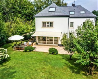 Située dans une impasse au calme, cette belle bâtisse datant de 1900, entièrement rénovée et isolée en 2007, se trouve, sans vis à vis, à l’entrée de village de Bissen sur un magnifique terrain de 21a 67ca. Elle bénéficie de ± 380m² dont ± 300m² de surface habitable.
 
La maison est composée comme suit :
 
Au rez-de-chaussée : d’une entrée principale ; d’un salon de ± 33m² avec sa cheminée traversante donnant sur la salle à manger de ± 20m² ; d’une cuisine équipée semi-ouverte ; d’une arrière-cuisine ; d’un wc séparé ; d’un salon TV ; d’une chambre d’amis de ± 13m² en-suite avec sa salle de douche. Le salon et la cuisine s’ouvrent sur une magnifique terrasse de ± 40m² en « L » avec marquise électrique avec des spots et chauffage infra-rouge extérieur.
 
Au 1er étage ; d’un palier ; d’une suite parentale avec sa salle de bain (baignoire, douche et toilette séparées) et son dressing ; 3 chambres avec leur salle de douche ; d’un wc séparé.
 
Au 2ème étage : d’une chambre avec sa salle de douche ; d’une chambre ; d’une chambre de 18m² aménagé en salle de sport et d’une pièce de rangement.
 
Le sous-sol : de 2 garages, de différentes caves et d'une chaufferie.
Devant le garage il y a une possibilité de parking pour 2-3 voitures.
 
 
Le jardin paysagé, orienté plein sud, propose un parking et plusieurs espaces de détente : terrasse ombragée, solarium avec jacuzzi, terrain de basket, terrasse ensoleillée, une partie boisée avec son chemin descendant vers un ruisseau.
 
Généralités :
 
Chauffage au gaz - Double vitrage en bois
Parquet massif et pierres naturelles
Orientation sud
Alarme
Accès direct à l’autoroute du Nord (3 minutes)
Ecole primaire, crèches et aire de jeux à pieds
Proximité de Mersch, du centre commercial Topaze, de la gare et à moins de 20 minutes du Kirchberg
 
ENGLISH VERSION
 
Located in a quiet cul-de-sac, this beautiful 1900 house, completely renovated and isolated in 2007, at the entrance to the village of Bissen on a beautiful plot of 21a 67ca, has a living space of ± 300m² / 3.000 sq. ft.
 
The house is composed as follows:
 
On the ground floor : a main entrance ; a 33m² living room with its fireplace communicating directly with the 20m² dining room ; a semi open fully equipped kitchen ; a scullery ; a TV room / lounge ; a guestroom with en-suite shower room and toilet ; and a separate toilet. The living room and the kitchen (via a wooden bridge) open onto a magnificent 40m² 