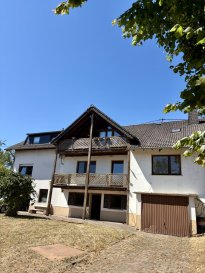 Dieses außergewöhnlich großzügige Einfamilienhaus in Harspelt bietet viel Platz, zahlreiche Nutzungsmöglichkeiten und ein beeindruckendes Grundstück mit rund 2500 Quadratmetern. Die Nähe zur luxemburgischen Grenze macht die Immobilie besonders interessant für Familien, Berufspendler und alle, die naturnah wohnen und gleichzeitig von der guten Erreichbarkeit Luxemburgs profitieren möchten.

Das im Jahr 1940 massiv erbaute Wohnhaus wurde 1988 erweitert und verfügt über rund 150 Quadratmeter Wohnfläche auf zwei Etagen. Insgesamt stehen neun Zimmer zur Verfügung, darunter sieben Schlafzimmer. Damit bietet das Haus außergewöhnlich viel Raum für eine große Familie, mehrere Generationen oder eine individuelle Nutzung mit Gästezimmern, Arbeitsbereichen und Hobbyräumen.

Im Erdgeschoss befinden sich fünf Schlafzimmer sowie ein Badezimmer. Die Räume bieten ausreichend Platz für eine große Familie, Gäste oder individuelle Nutzungsmöglichkeiten.

Über die Treppe gelangt man in das erste Obergeschoss. Hier befindet sich der großzügige und offen gestaltete Wohn und Essbereich mit angrenzender offener Einbauküche. Ein gemütlicher Kaminofen aus Speckstein sorgt für eine besonders behagliche Atmosphäre und macht den Wohnbereich zu einem einladenden Mittelpunkt des Hauses.

Vom Wohnbereich aus gelangt man auf den Balkon. Von hier eröffnet sich eine wunderschöne Fernsicht über die umliegende Landschaft bis ins Ourtal. Der Ausblick verleiht diesem Wohnbereich eine ganz besondere Wohnqualität.

Ergänzt wird das Raumangebot durch weitere Schlafzimmer sowie zusätzliche Räume und Badezimmer. Das Haus verfügt insgesamt über sieben Schlafzimmer und drei Badezimmer.

Die Immobilie verbindet großzügiges Wohnen, eine idyllische Lage und ein außergewöhnlich großes Grundstück mit der Nähe zu Luxemburg. Gerade für Familien und Grenzgänger bietet diese Kombination ein hohes Maß an Lebensqualität und langfristigem Potenzial. Harspelt liegt idyllisch im westlichen Eifelkreis Bitburg-Prüm und überzeugt durch seine besondere Lage nahe dem Dreiländereck Deutschland-Luxemburg-Belgien. Die luxemburgische Grenze sowie Belgien sind in wenigen Minuten erreichbar. Die Gemeinde Weiswampach in Luxemburg liegt nur etwa 7 Kilometer entfernt, Burg Reuland in Belgien etwa 6 Kilometer.

Daleiden erreichen Sie in etwa 8 Kilometern, Arzfeld in etwa 10 Kilometern und Prüm in etwa 25 Kilometern. Bitburg liegt rund 35 Kilometer entfernt.

Die ruhige und naturnahe Lage mit herrlichen Landschaften, viel Erholungswert und gleichzeitig kurzen Wegen nach Luxemburg und Belgien macht Harspelt besonders attraktiv für Familien, Naturliebhaber und Berufspendler.

Die Stadt Luxemburg ist je nach Fahrstrecke in etwa 65 bis 75 Kilometern erreichbar.