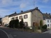 Maison Vente 5 chambres à Ellange - 485 000 € Altes Haus im Dorfkern von Ellange zum Renovieren mit viel Potential, direkt an der Natur.
Das alte Haus wurde in den letzten 100 Jahren öfters renoviert und bietet auf Grund seiner Grösse viel Potential. Im Erdgeschoss des Haupthauses ( 70m2 ) liegen das Wohnzimmer, das Esszimmer, die grosse Küche und ein Treppenhaus mit Flur. Im ersten Stock finden sich 3 Schlafzimmer mit Badezimmer, im 2.Stock ein teilausgebauter Speicherraum.
Im Anbau gibt es eine Garage, den Heizungskeller mit Buderus Mazoutheizung und Holzheizung, eine Werkstatt und ein weiterer Abstellraum mit Treppe zum ersten Stock des Anbaus. Hier befinden sich 2 Schlafzimmer und ein Speicherraum im hinteren Teil des Anbaus. Im 2.Stock des Anbau gibt es einen weiteren Speicherraum. Das Haus ist nicht unterkellert. Die Fenster sind alt aber doppelt verglast. Hinter dem Haus ist ein kleiner Hof, seitlich und vorne ein kleiner Garten mit Wiese. Der Aussenparkplatz findet sich vor der Garage.
Ellange ist einer der zwei Dörfer die zur Gemeinde Mondorf-les-Bains gehören. Hier gibt es im oberen Teil einen Smatch Supermarkt. Alle anderen Einkaufsmöglichkeiten, Schulen und Sportaktivitäten gibt es in Mondorf-les-Bains. Das Haus liegt nur einige Meter von Wiesen und Feldern entfernt. Die Mosel mit ihren berühmten Weinbergen sind in wenigen Autominuten erreichbar.